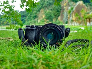 black sony dslr camera on green grass in front of brown and green mountain